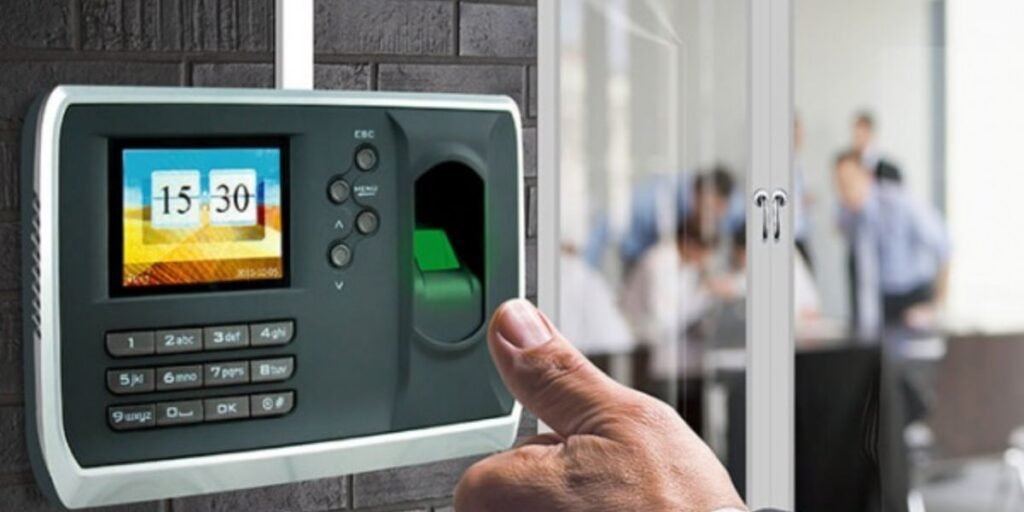Person using a biometric fingerprint scanner for attendance outside a glass-walled office meeting room.