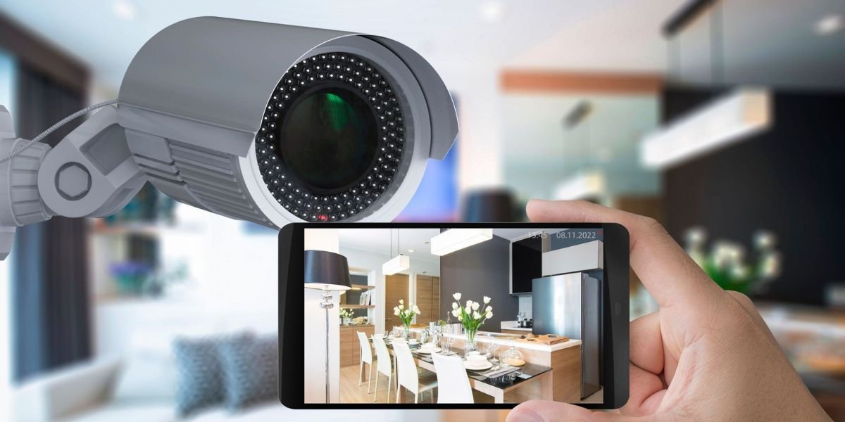 Hand holding smartphone showing live feed from a CCTV security camera inside a modern home