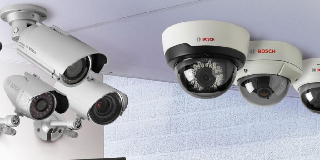 A display of several white Bosch security cameras, including bullet cameras and dome cameras.