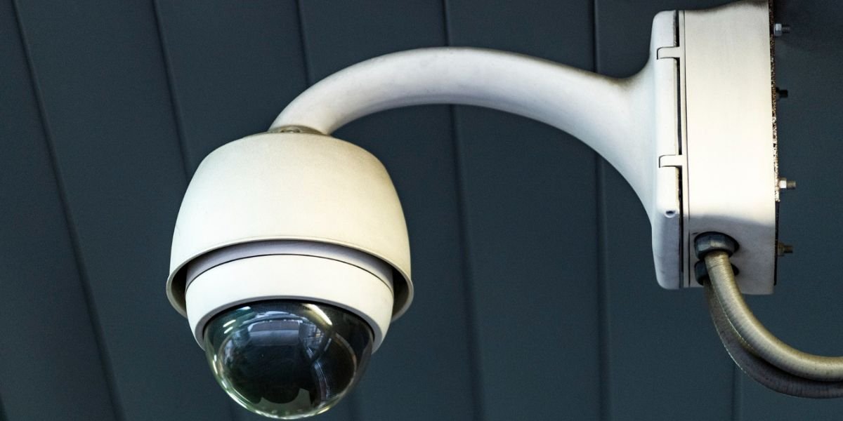 Close-up of a white dome-style outdoor security camera mounted on a dark surface